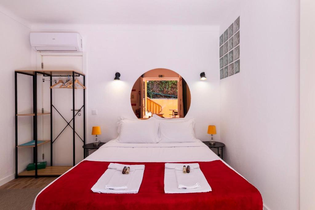 Cama de casal com espelho redondo e roupa de cama branca e vermelha