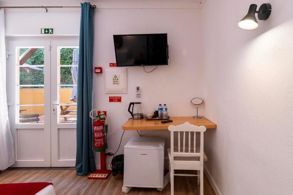 Zona de trabalho com secretária, TV, chaleira e frigorífico