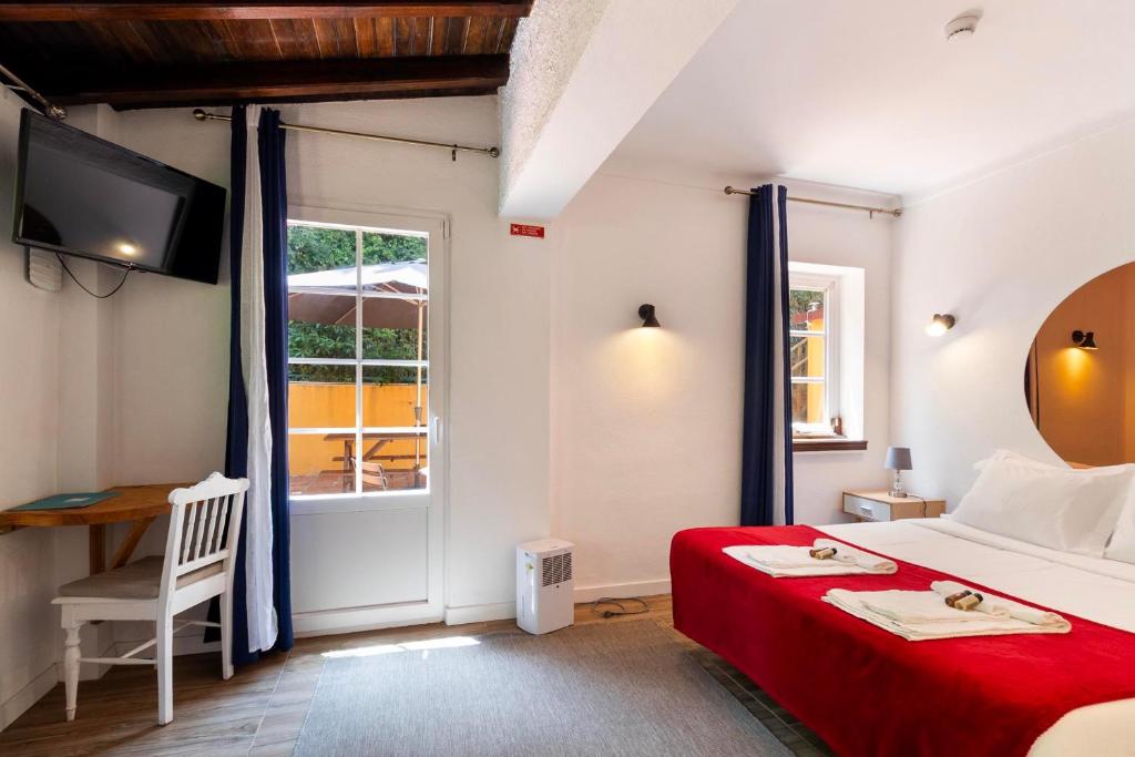 Quarto com TV, secretária e saída para o terraço
