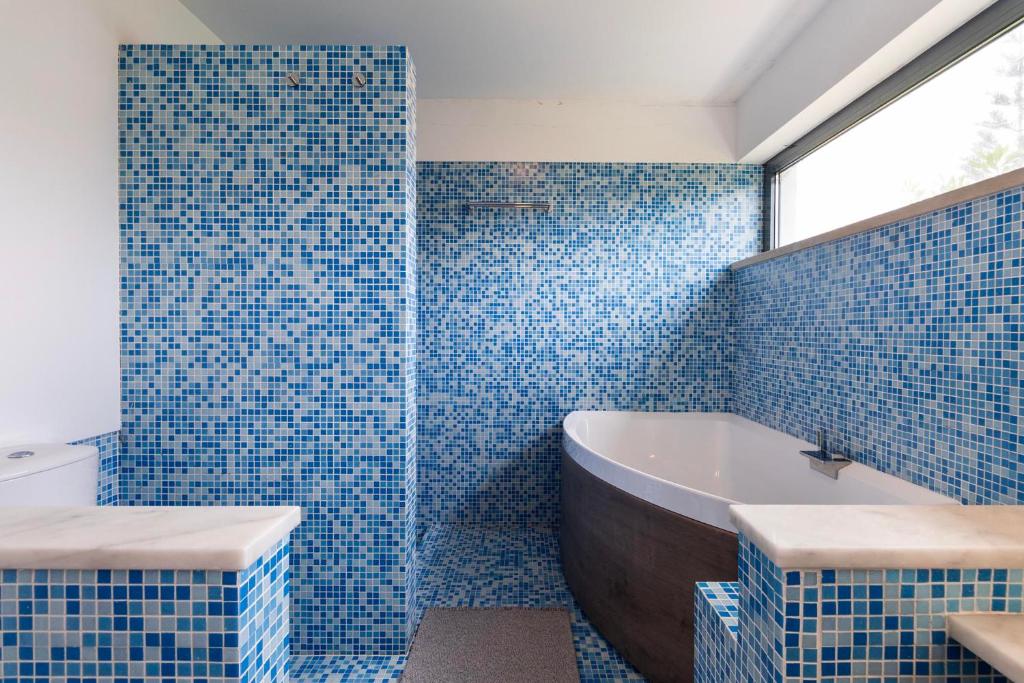 Banheira e duche em mosaico azul com luz natural
