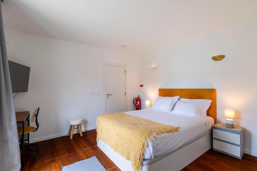 Suite com cama de casal, cabeceira em madeira e manta amarela