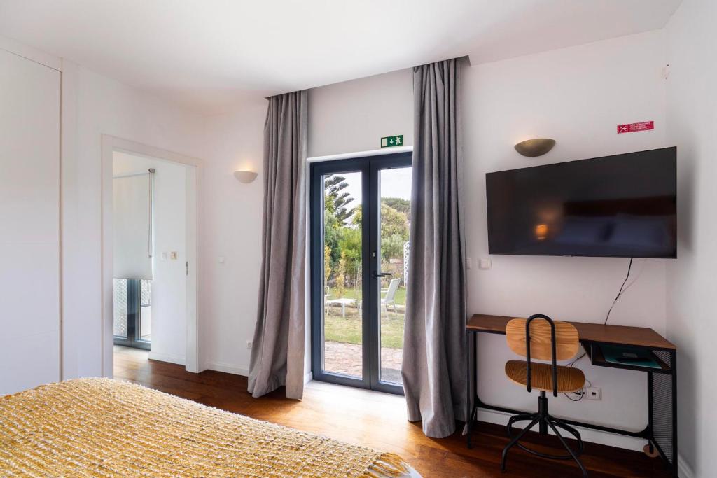 Quarto com TV, secretária e porta para o jardim