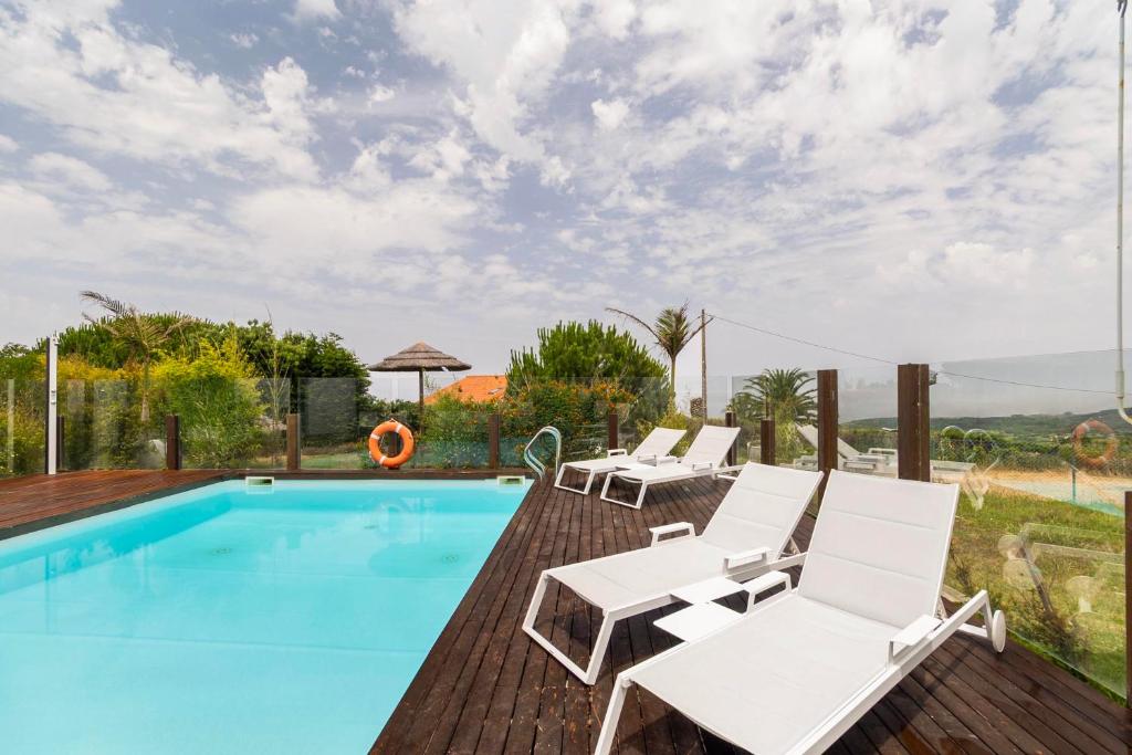 Piscina com espreguiçadeiras e guarda-sol de colmo