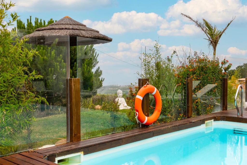 Piscina com guarda-sol de colmo e jardim envolvente